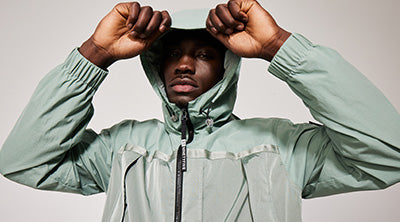 Model wearing the ST95 Archive Anorak in sage green, featuring hooded design, zip closure, and lightweight fabric.