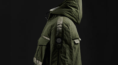Side view of the ST95 Proximity Parka in olive green, featuring a hood, sleeve logo patch, and utility pocket detail.