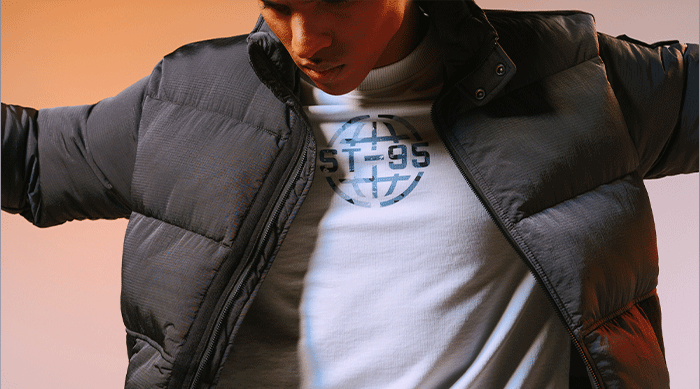 Model wearing the ST95 Puffa Jacket in black, featuring quilted insulation and front zip fastening over logo T-shirt.