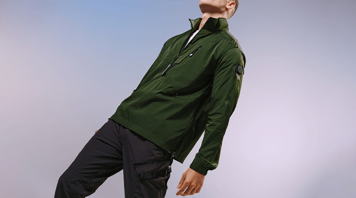 Model wearing the ST95 Overshirt 02 in green, featuring quarter zip fastening, chest pocket, and sleeve logo badge.