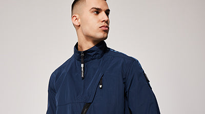 Model wearing the ST95 Uplink Overshirt in navy, featuring asymmetric zip detail and sleeve logo patch.