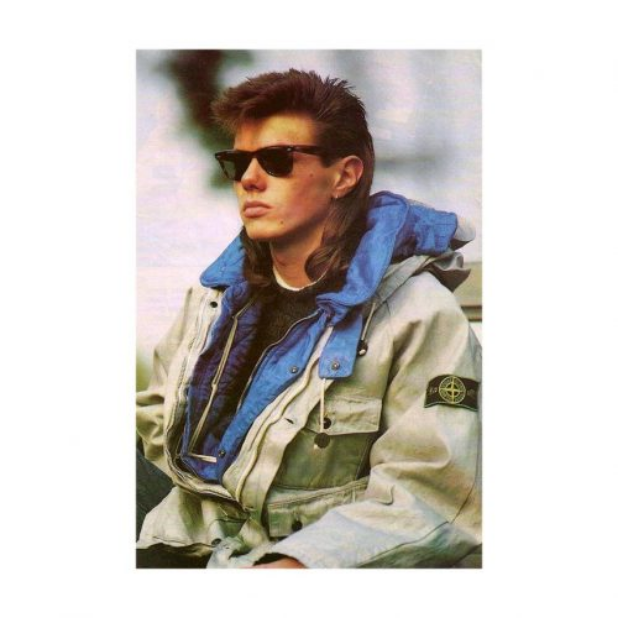 1982 Stone Island promotional image showing a model wearing a light jacket with blue lining and signature arm badge.
